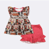 A toddler girl's two-piece outfit set consisting of a tiered smocked dress with a western cow print and matching ruffled shorts in a solid coral pink color, laid flat on a white background.
