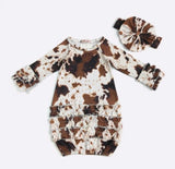 Cow print baby romper with matching hat on a white background