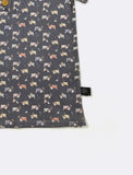 Fabric with vintage tractor pattern on a dark background, folded neatly with a brand tag.