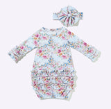 A baby long-sleeve romper and matching headband set with a whimsical castle and floral print on a light blue background, displayed flat against a white background.