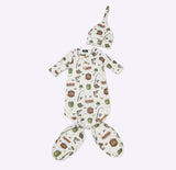 A baby sleep suit and matching bonnet set with an all-over printed pattern of woodland animals and picnic items on an off-white background, displayed flat against a light gray studio background.