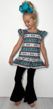 Young girl wearing a patterned dress and black pants against a white background
