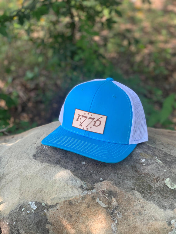Blue trucker hat with a leather patch on the crown with 1776 on it
