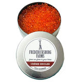 A small, round tin Fredericksburg Farms air freshener with a orange solid color interior, labeled 'Cream Brulee'.