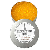A small, round tin Fredericksburg Farms air freshener with a yellow solid color interior, labeled 'You are my sunshine'.