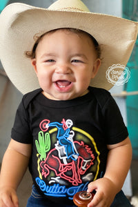 Onsie for toddler with neon rodeo sign outta hand being worn by a little boy with a cowboy hat