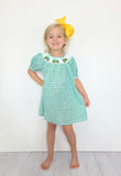 Green smocked short sleeved dress with tractors around the collar - youth model with yellow bow