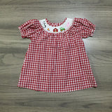 Red gingham farm dress by Clover Cottage layed out on on display 