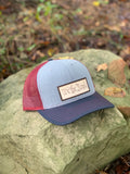 Red, grey, and blue trucker style hat with a leather patch which reads We the People front