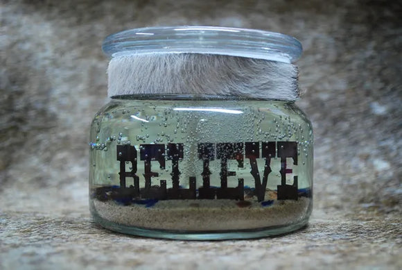 Small gel candle with the word believe cutout of metal in the center.