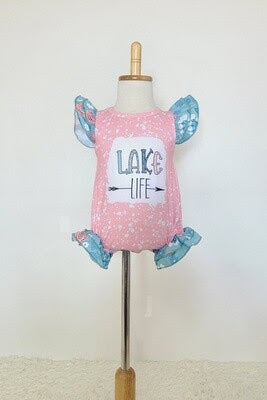 Lake Life romper. Pink and teal colors with white paint splatter design on body of romper. Made by Clover Cottage.